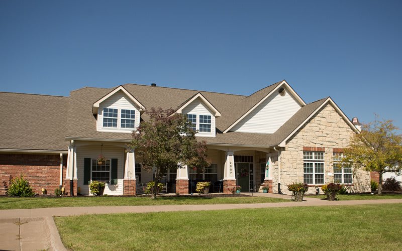 A suburban residential house with a well-maintained lawn under a clear blue sky.