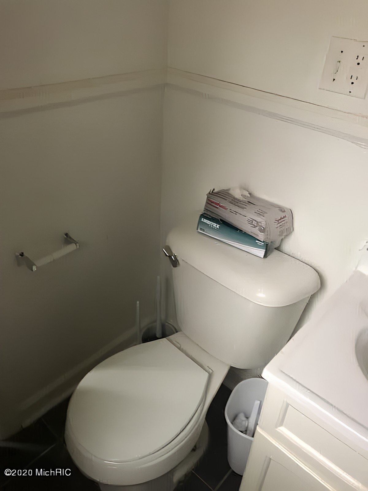 A small bathroom with a toilet, tissue box, and an empty toilet paper holder.