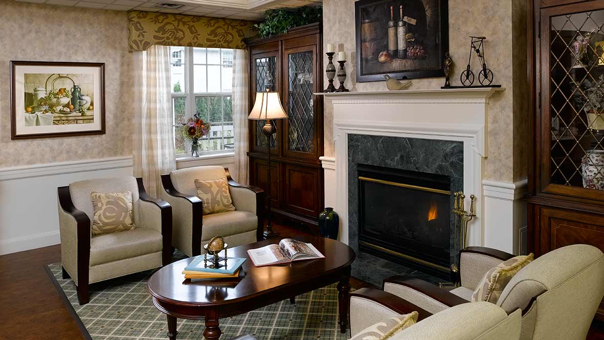 A cozy living room with elegant furniture, a fireplace, and artwork above the mantel.