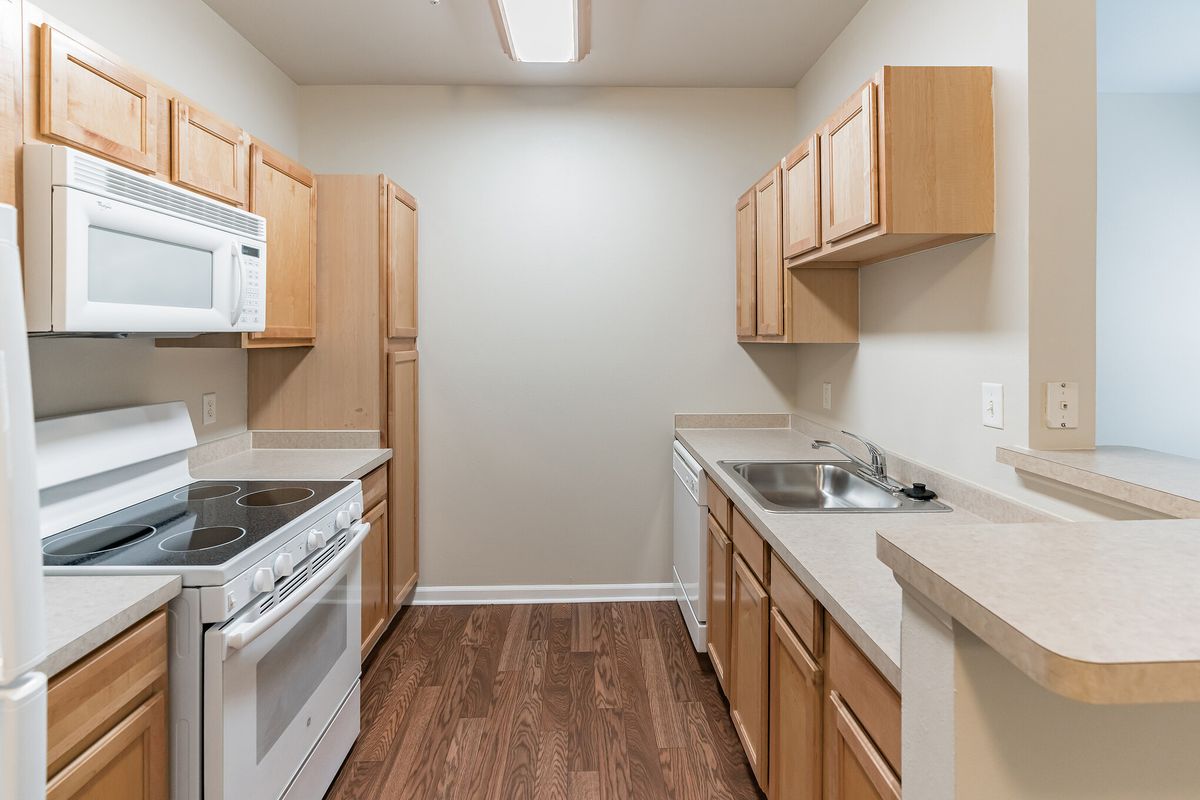 A small apartment kitchen with wooden cabinets and a stove.