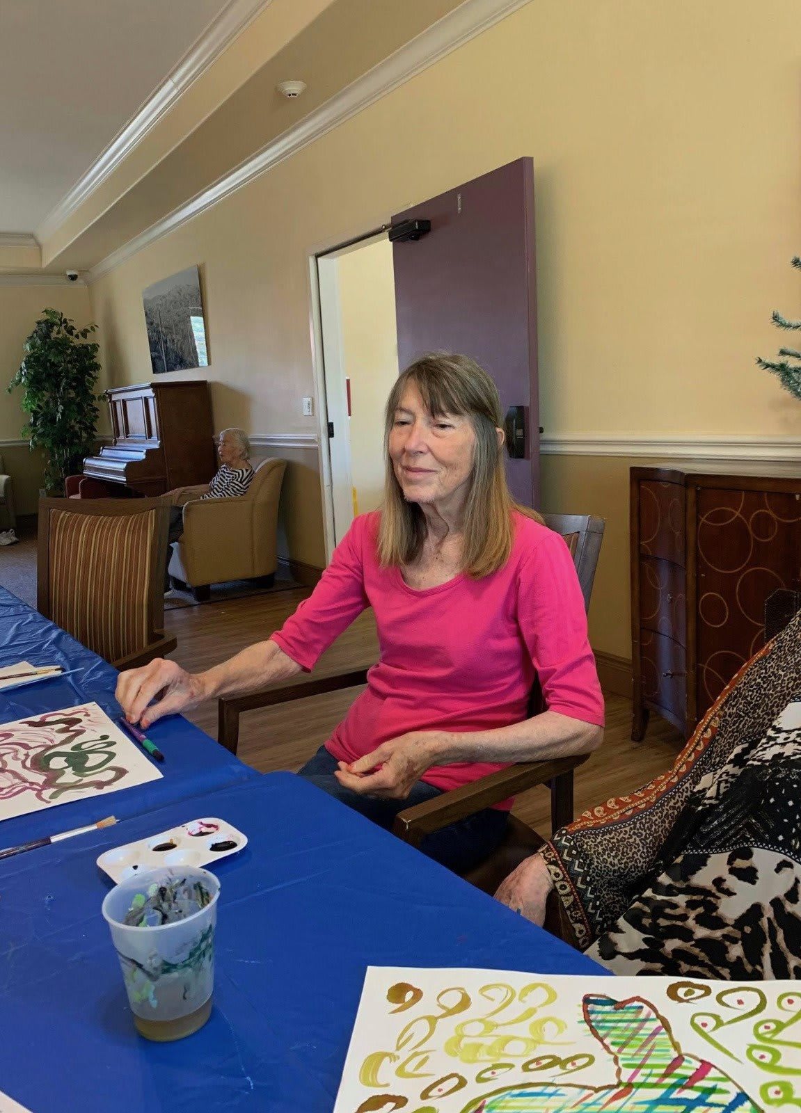 A woman engaged in an art activity at a table indoors.