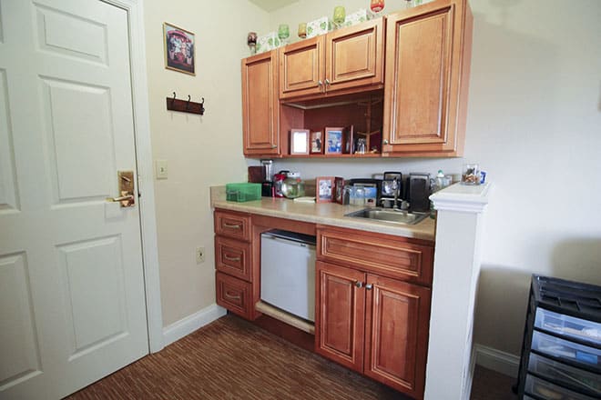 A small kitchen area with wooden cabinets, a sink, and various appliances on the countertop.