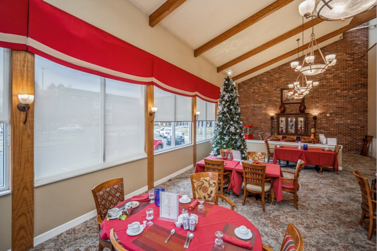 A festive restaurant dining area with red tablecloths and a decorated Christmas tree.