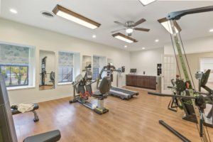 A modern indoor gym with exercise equipment including treadmills and an elliptical machine.