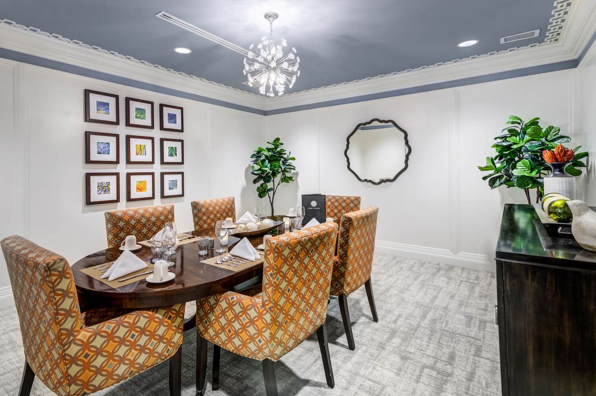 A stylish dining room with elegant furnishings and decor, featuring a chandelier and wall art.