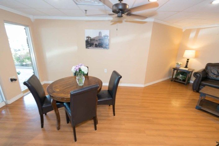 A cozy dining area featuring a round wooden table with leather chairs, set on a hardwood floor, and a decorative vase with flowers in the center.