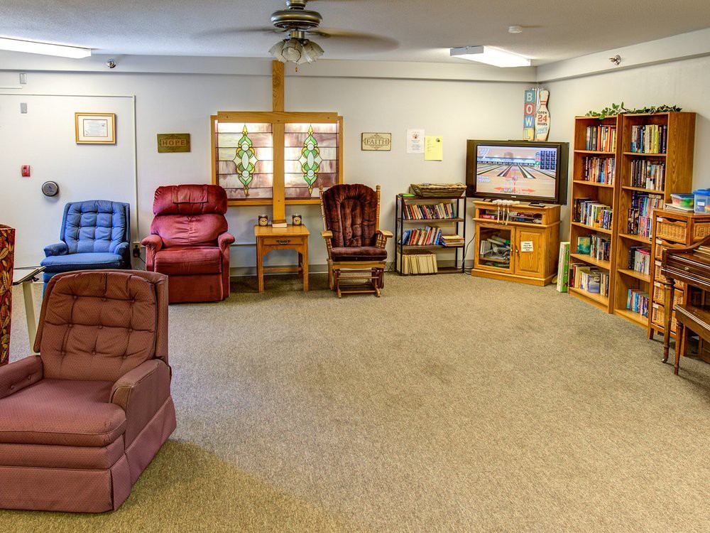 A cozy living room with armchairs, a television, and bookshelves.