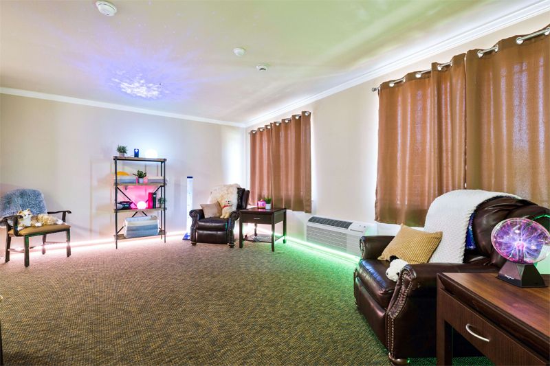 A cozy living room with two chairs, warm lighting, and floor-length curtains.