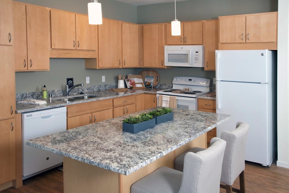 A modern kitchen with wood cabinets, granite countertops, and an island with seating.