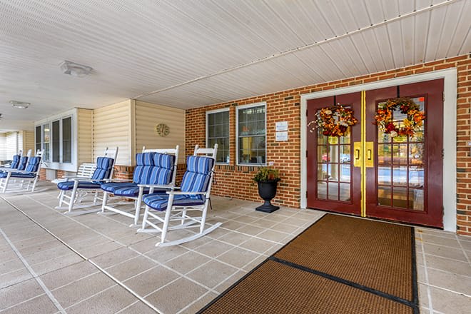 A welcoming entrance with rocking chairs and festive wreaths on double doors.