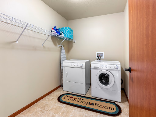 A well-organized laundry room featuring a washer and dryer, with shelves for storage and cleaning supplies.