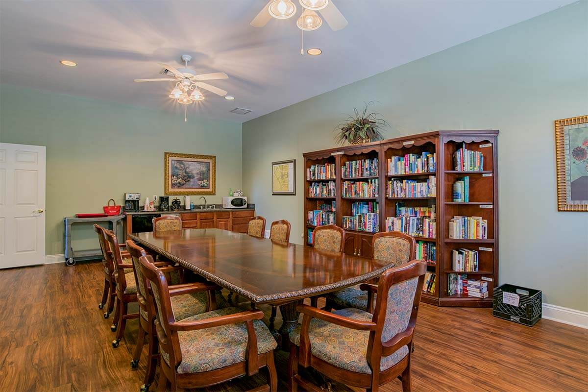 A well-furnished conference room with a large meeting table, surrounded by bookshelves filled with books.