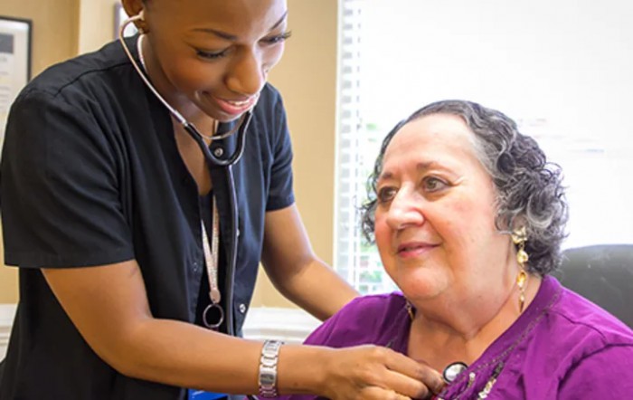 A healthcare professional using a stethoscope to examine a patient during a medical consultation.