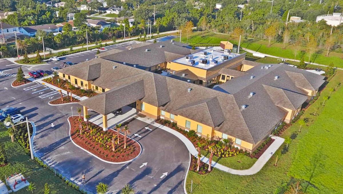 Aerial view of a large building with a well-maintained driveway and surrounding greenery.