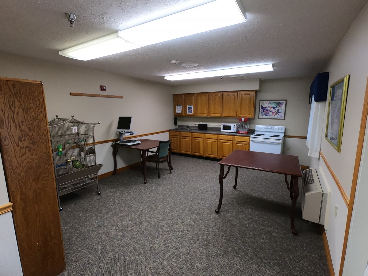 An office space with desks, a computer, cabinets, and tables under bright lighting.