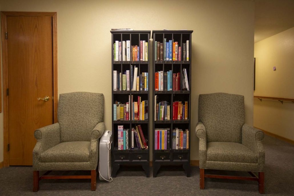 A cozy reading area with a bookshelf flanked by two comfortable chairs.