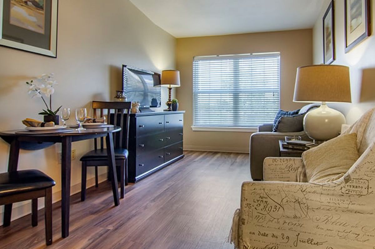 A cozy living room with a sofa, television, and a small dining area near the window.