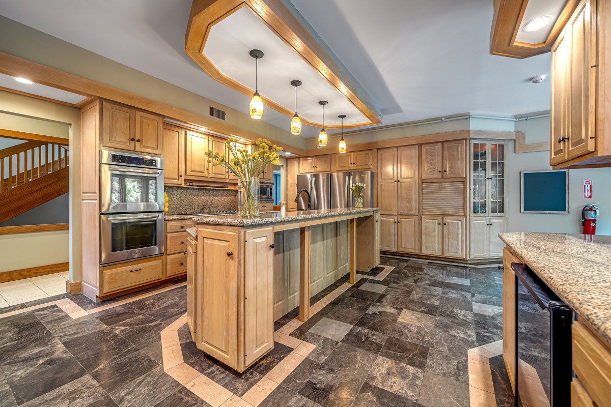 A modern kitchen with wooden cabinets, an island, and pendant lighting.