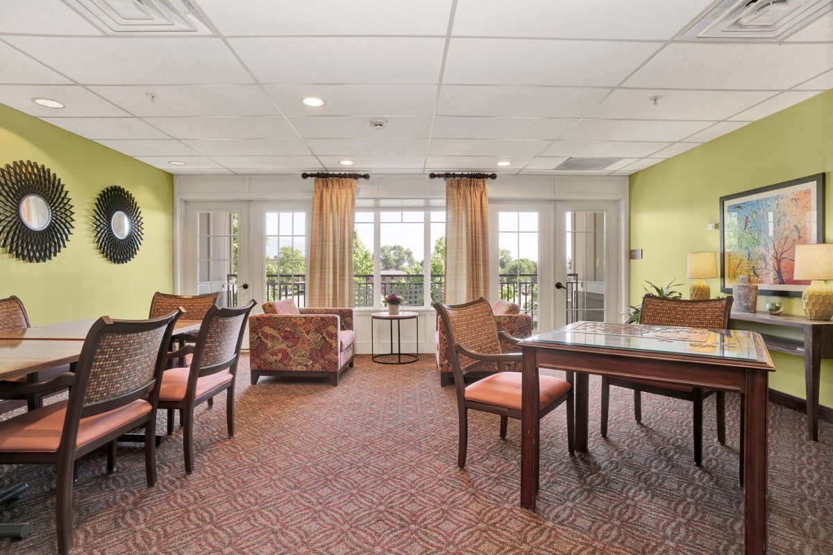 A bright, cozy living room with tables, chairs, and large windows.