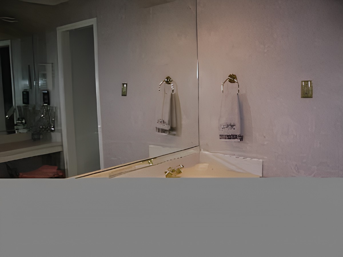 A bathroom with a mirror, sink, and a towel hanging on the wall.