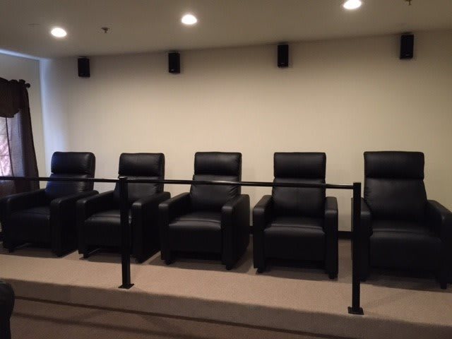 A row of black recliner chairs in a home theater setting.