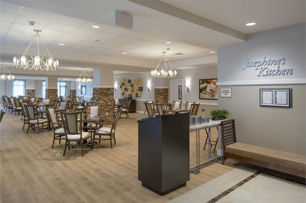 A modern dining area with elegant chandeliers, neatly arranged tables and chairs, and stylish decor.