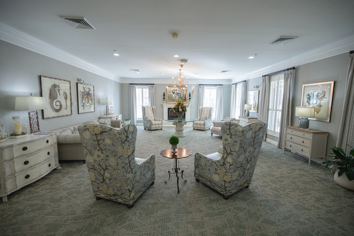 An elegantly designed living room with plush chairs arranged in a cozy setting and a central chandelier.
