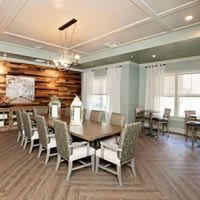 A modern dining room with a large table and chandelier, featuring wood flooring and neutral-colored decor.