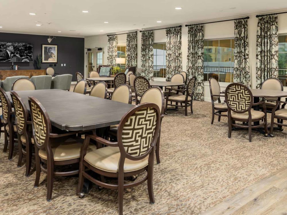 A well-furnished dining room with elegant chairs and tables, complemented by patterned curtains and carpet.