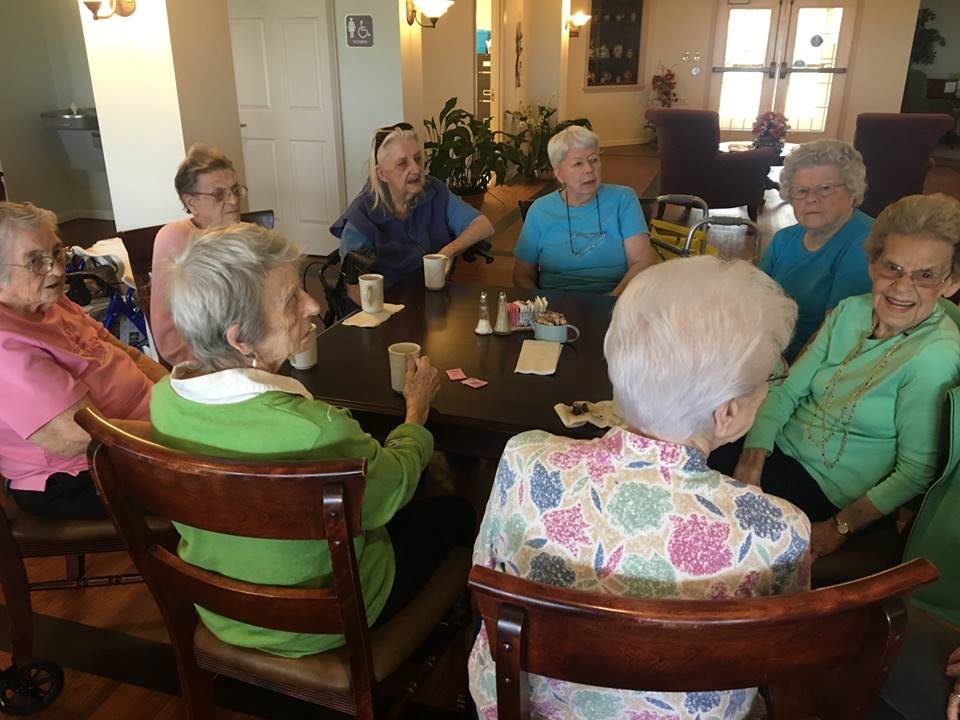 A group of seniors gathered around a table enjoying a social gathering.