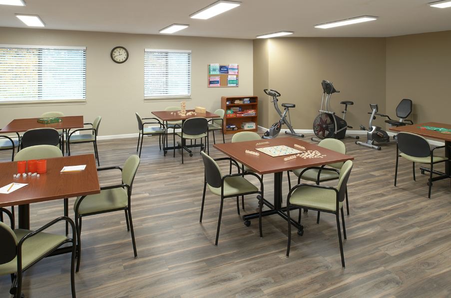 A multipurpose activity room with tables, chairs, and exercise equipment.