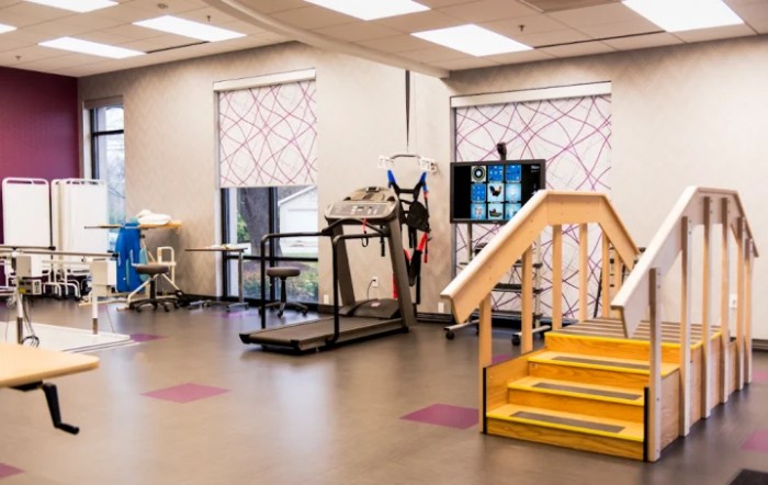 A rehabilitation facility featuring exercise equipment and a mini staircase for physical therapy purposes.
