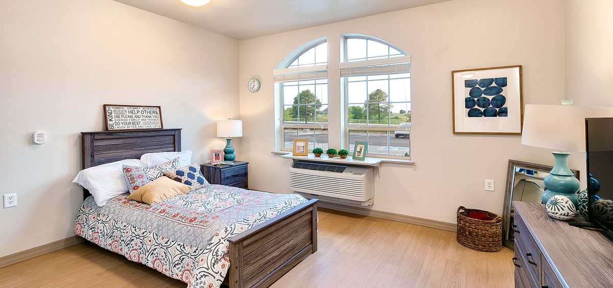 A cozy bedroom with a large window, featuring a neatly made bed and stylish decor.