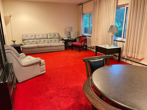 A cozy living room featuring a gray sofa, a round table, and vibrant red carpet.