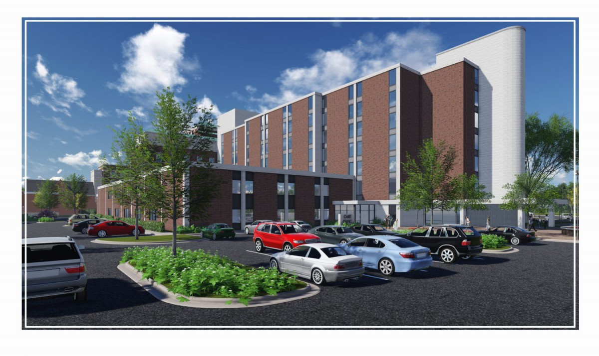 A modern building with a parking lot featuring several cars, set against a blue sky.