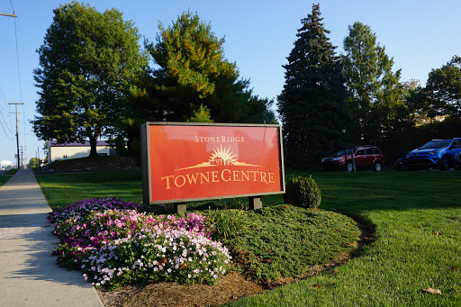 A welcoming sign at Towne Centre, surrounded by vibrant flowers and lush greenery.