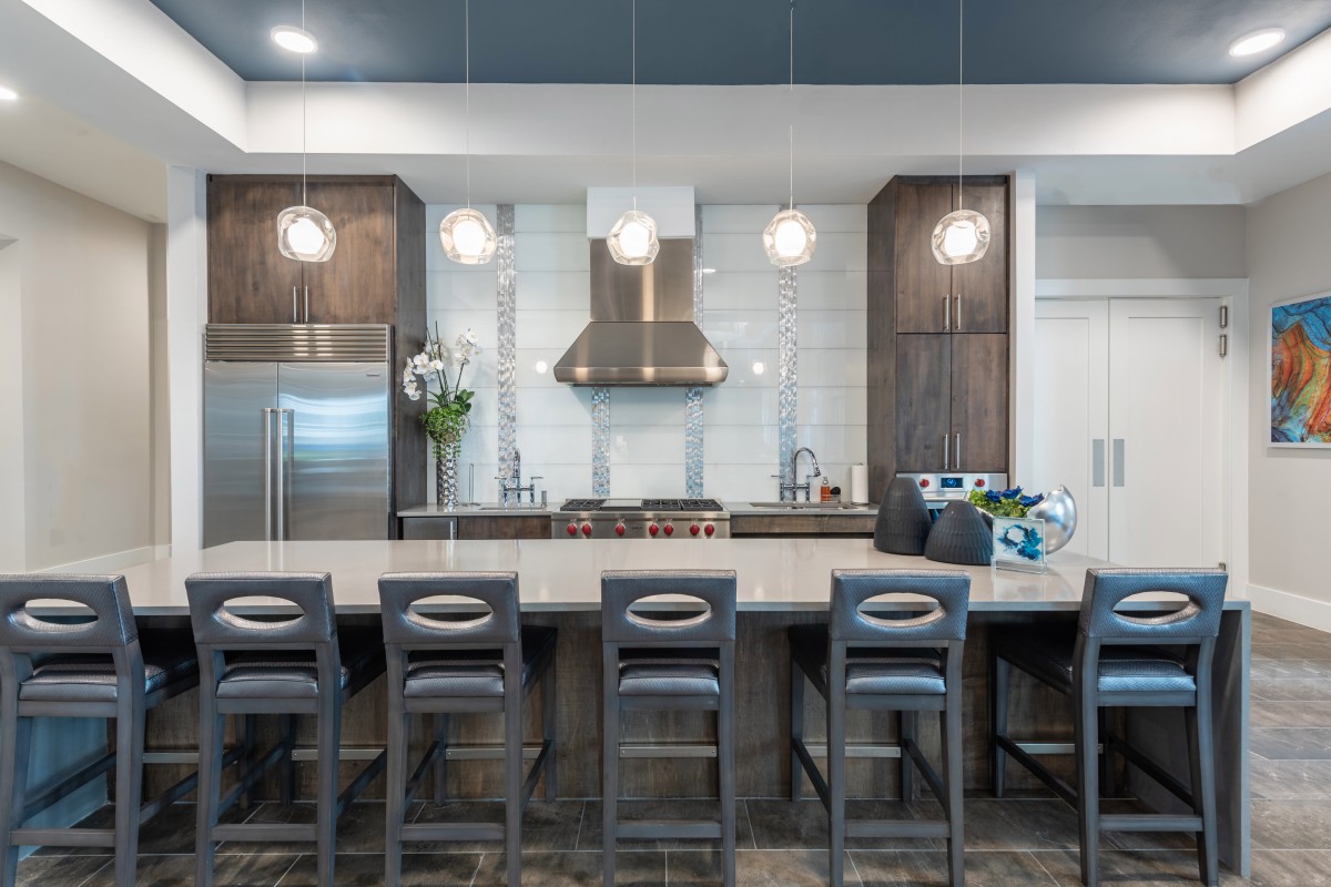 A modern kitchen with sleek bar stools and pendant lighting.