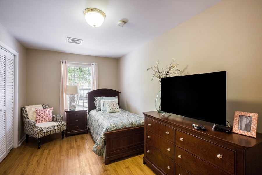 A cozy bedroom with a single bed, dresser, and a TV on top.