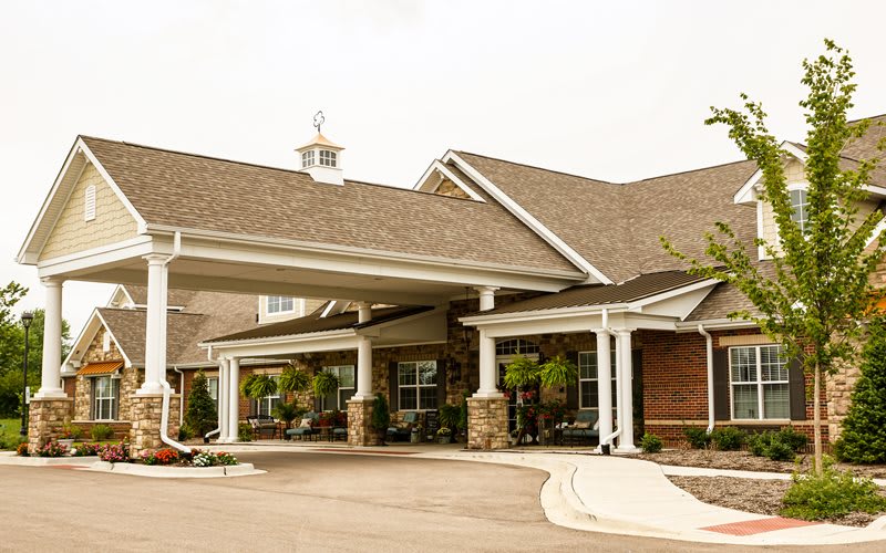 A view of a residential building with a covered entrance and landscaped driveway.