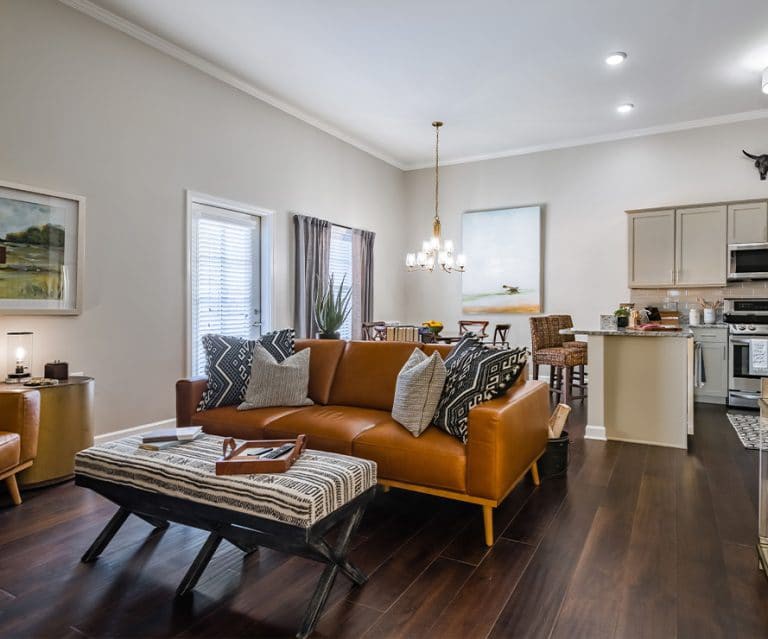A modern living room with an open floor plan featuring a brown leather sofa and stylish decor.