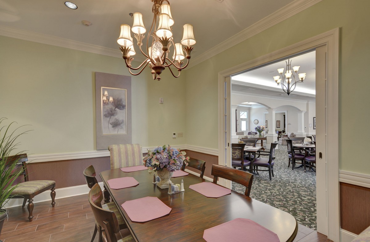 An elegant dining room with a chandelier and table set for a meal.
