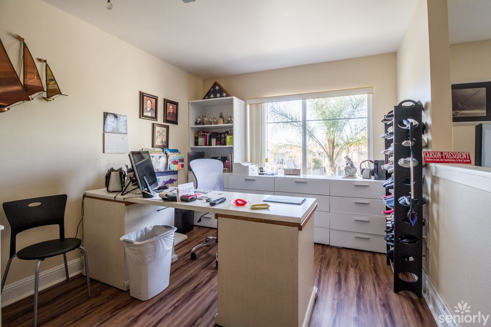 A well-organized home office with a desk and computer near a large window.