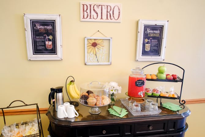 A bistro setup with breakfast items such as fruit, muffins, and drinks on display.