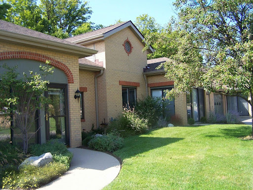 A beautifully landscaped residential house with a well-maintained lawn and trees.
