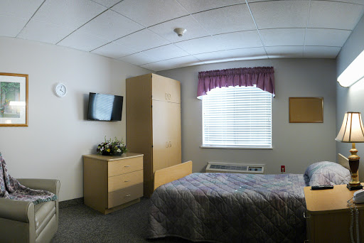 A cozy hotel room featuring a bed, television, and natural light coming through the window.