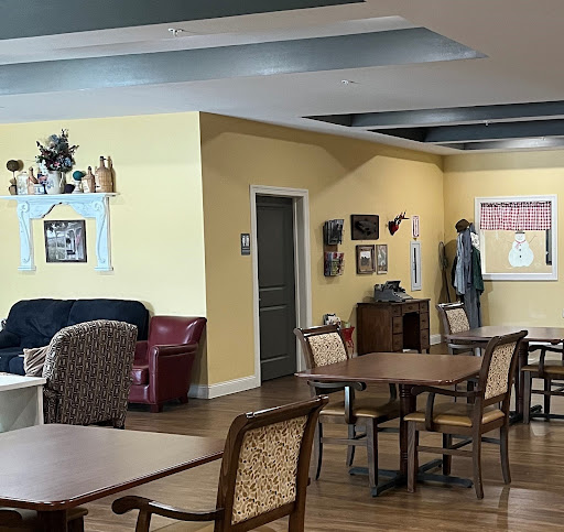 A cozy lounge area in a care facility, featuring comfortable seating and tables for socializing.