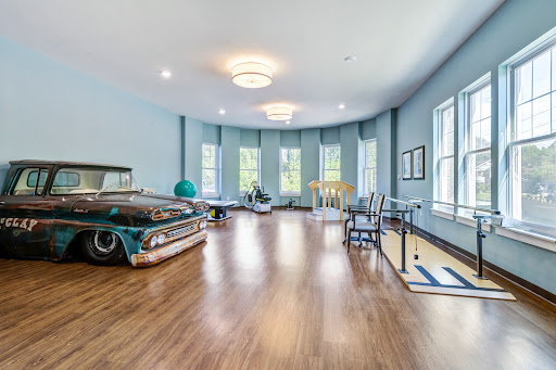 A spacious room featuring light blue walls and a vintage car, complemented by modern furnishings and ample natural light.