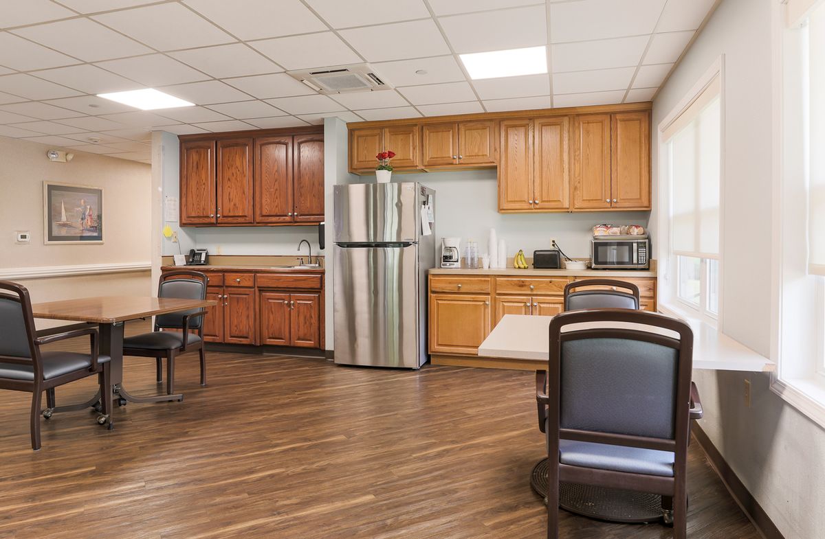 A modern kitchen area with wooden cabinets, stainless steel appliances, and dining furniture.