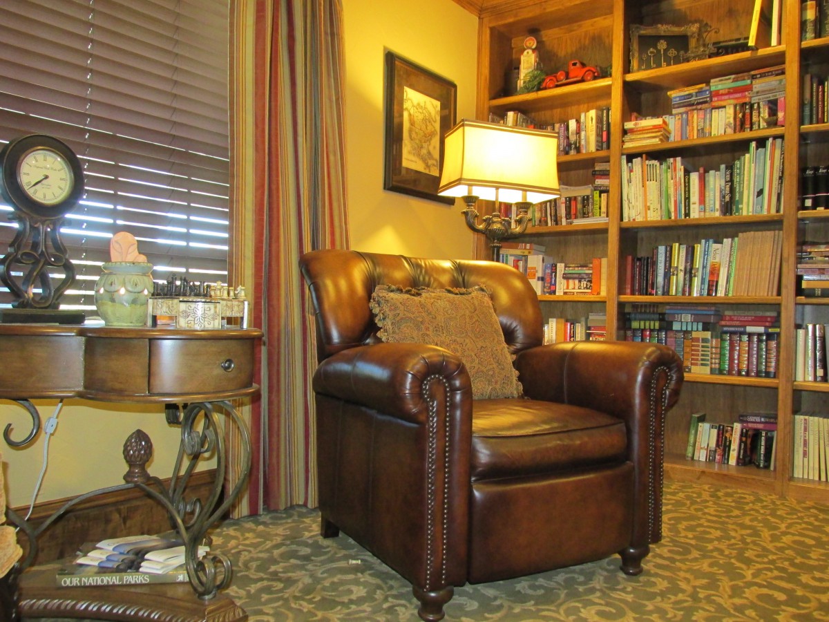 A cozy living room corner featuring a leather armchair and a well-stocked bookshelf.