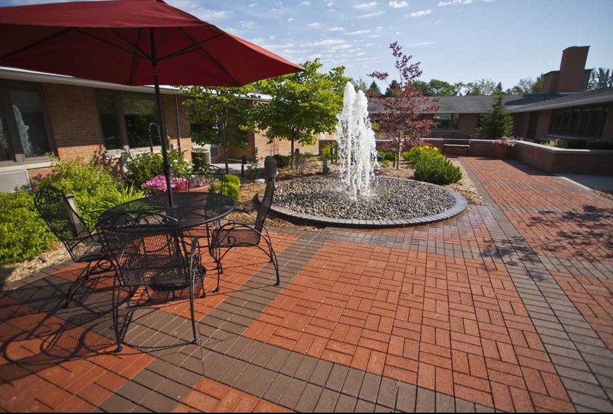 A serene patio area with a central fountain, surrounded by outdoor seating and lush greenery.